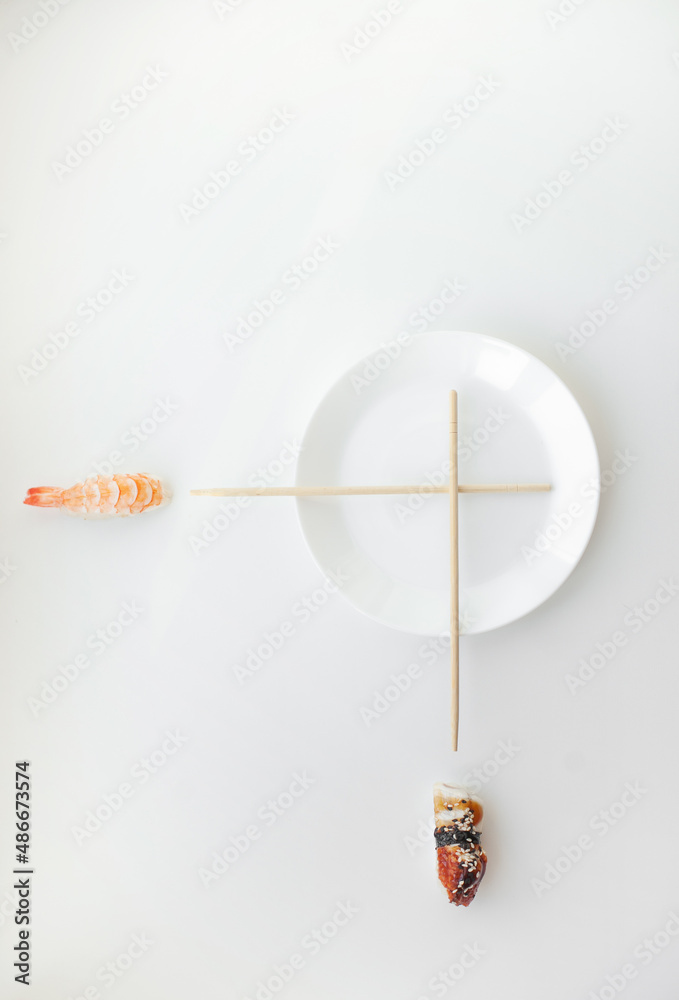 Sushi time concept - white plate and chopsticks as clock with nigiri sushi isolated on white.Concept time for sushi - nigiri and unagi sushi japan food on white with white plate and chopsticks.