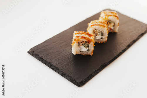 Sushi japan food on black plate at sushi restaurant or takeout with chopsticks on white. Delicious sushi japanese food with chopsticks fresh at the restaurant or takeout delivery.