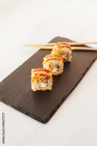 Sushi japan food on black plate at sushi restaurant or takeout with chopsticks on white. Delicious sushi japanese food with chopsticks fresh at the restaurant or takeout delivery.