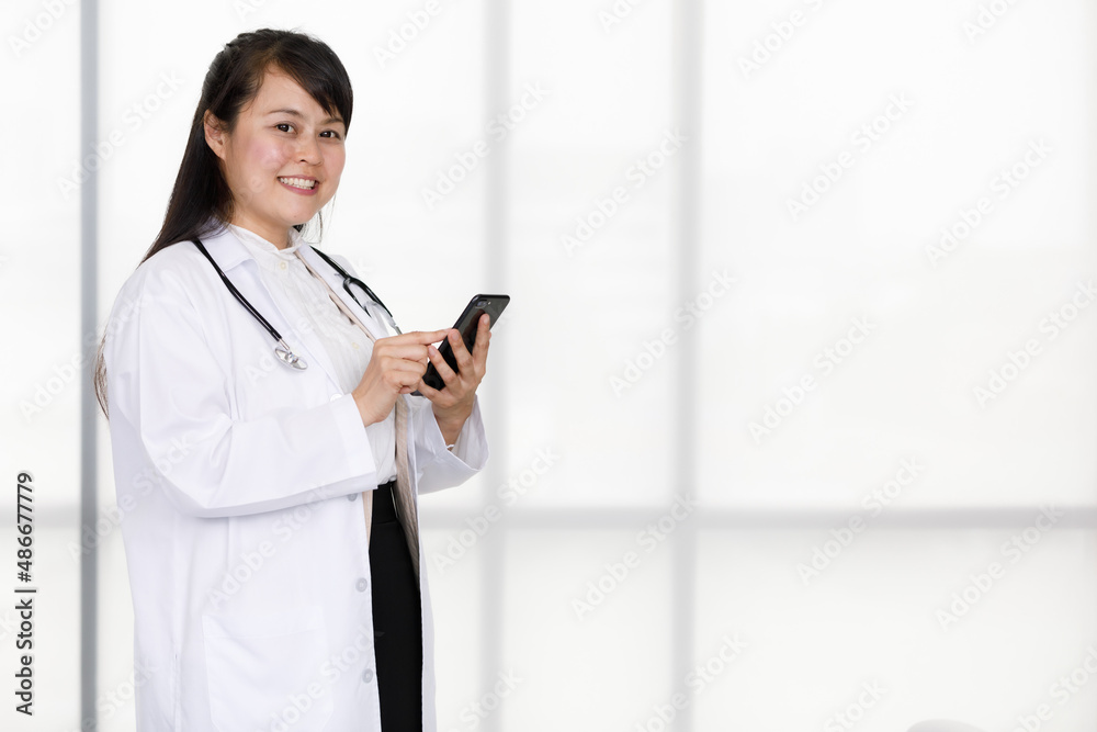 Portrait shot of Asian young happy professional successful experienced female doctor in white lab coat uniform with stethoscope standing on floor posing smiling look at camera Portrait shot of Asian young happy professional successful experienced female doctor in white lab coat uniform with stethoscope standing on floor posing smiling look at camera