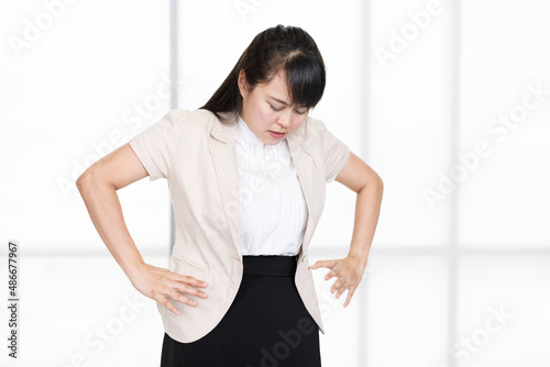 Asian young suffering painful frowning face female patient standing holding two hands squeezing on stomach having emergency menstrual pain stomachache tummyache rushing to see doctor in hospital photo