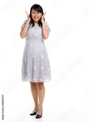 Portrait studio cutout isolated full body shot of Asian young happy trendy female model in beautiful gray lace dress standing posing holding hand on waist smiling look at camera on white background © Bangkok Click Studio