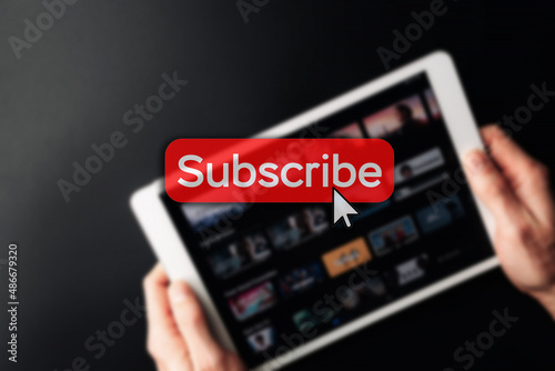 Subscription icon. Online video red subscribe button. Internet service on laptop digital tablet blured technology background. Social media concept. Streaming video. photo