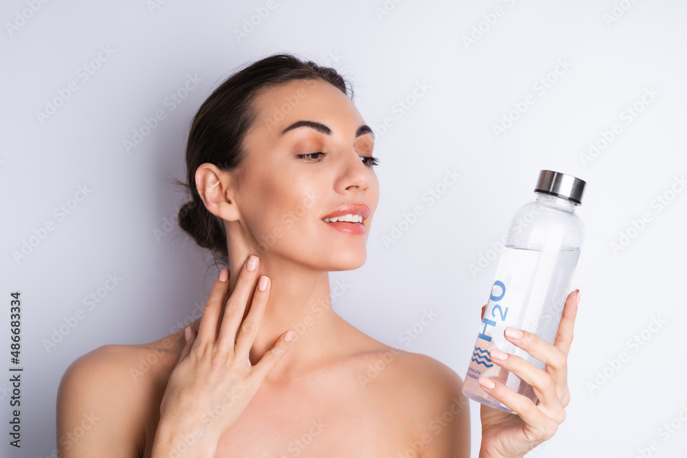 Close beauty portrait of a topless woman with perfect skin and natural make-up, holding personal glass bottle of h2o water, on a white background. Close beauty portrait of a topless woman with perfect skin and natural make-up, holding personal glass bottle of h2o water, on a white background.