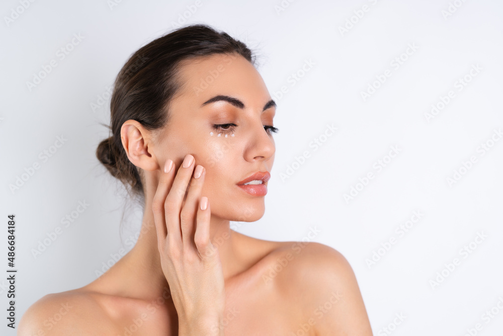 Close-up beauty portrait of a topless woman with perfect skin and natural make-up, with anti-aging cream dots to moisturize and firm the skin under the eyes. Close-up beauty portrait of a topless woman with perfect skin and natural make-up, with anti-aging cream dots to moisturize and firm the skin under the eyes.