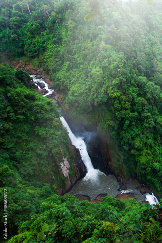 The tropical waterfall surrounded by green tropical forest.