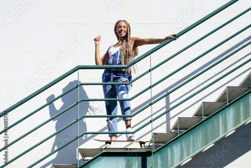 Young black woman on an urban staircase, with colourful braids. Typical African hairstyle.