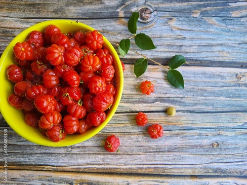 The Pitanga or Brazilian cherry, is the fruit of the Pitangueira, in a yellow bowl on a table. It is originally from Brazil. The word “pitanga” comes from the Tupi-Guarani, which means red. photo