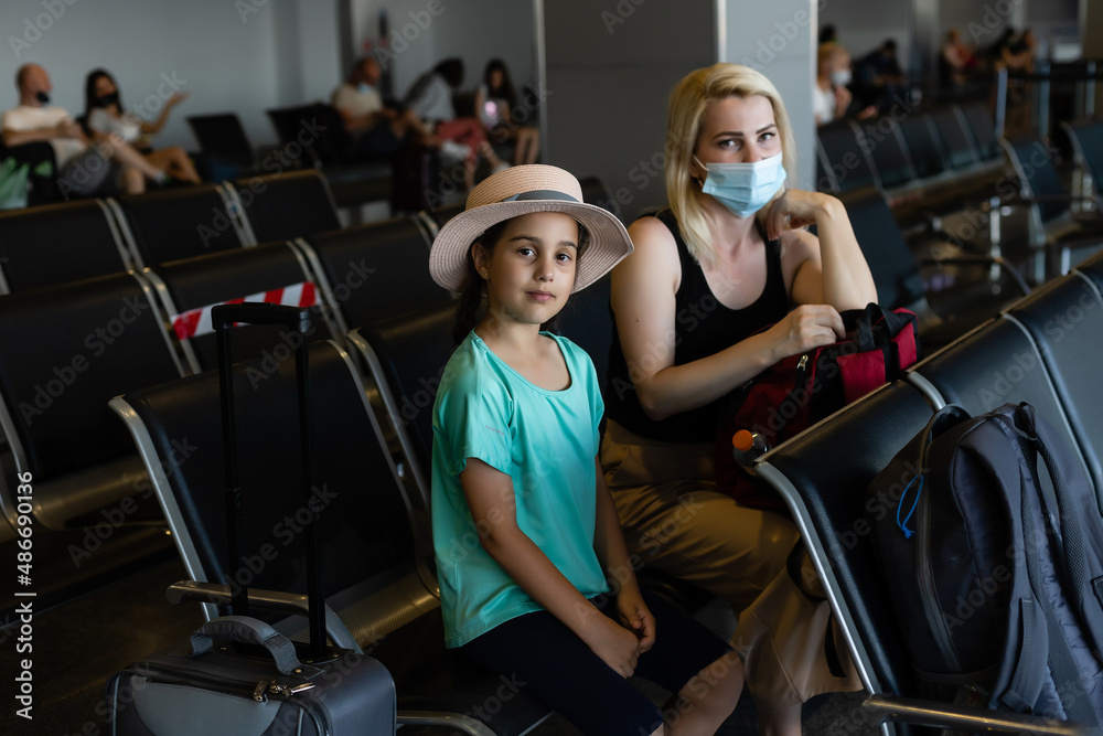 Fototapeta premium happy young mother with daughter at airport while waiting for their flight