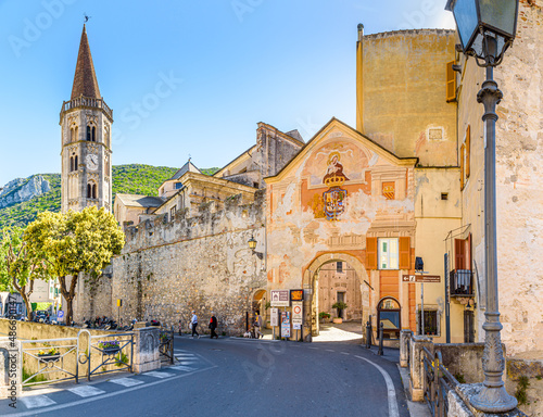 Fototapeta Naklejka Na Ścianę i Meble -  Finalborgo, Finale Ligure, Italy. May 5, 2021. View of the external facade of Porta Reale and of the ancient walls with the bell tower of the Church of San Biagio on the left.