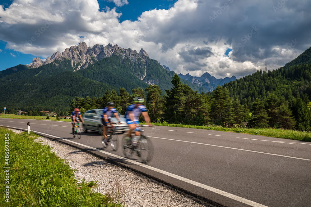 Cyclists riding a bicycle on the road in the background the Dolomites Alps Italy.