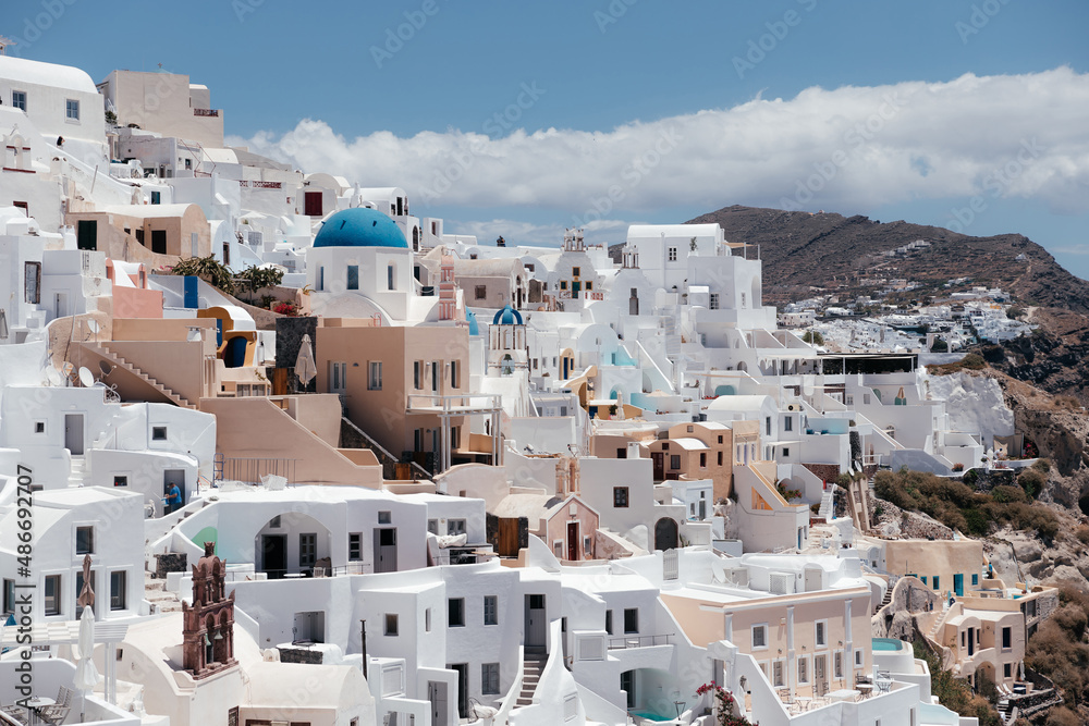 View of Oia town with church and blue dome in Santorini island in Greece. Summer vacation and holiday concept, luxury travel. Wonderful scenery, cruise ships and white architecture. Amazing landscape