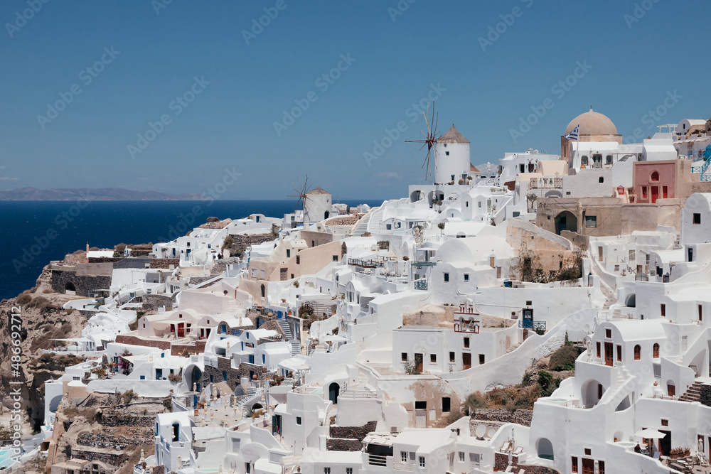 View of Oia town with mills in Santorini island in Greece. Summer vacation and holiday concept, luxury travel. Wonderful scenery, cruise ships and white architecture. Amazing landscape.