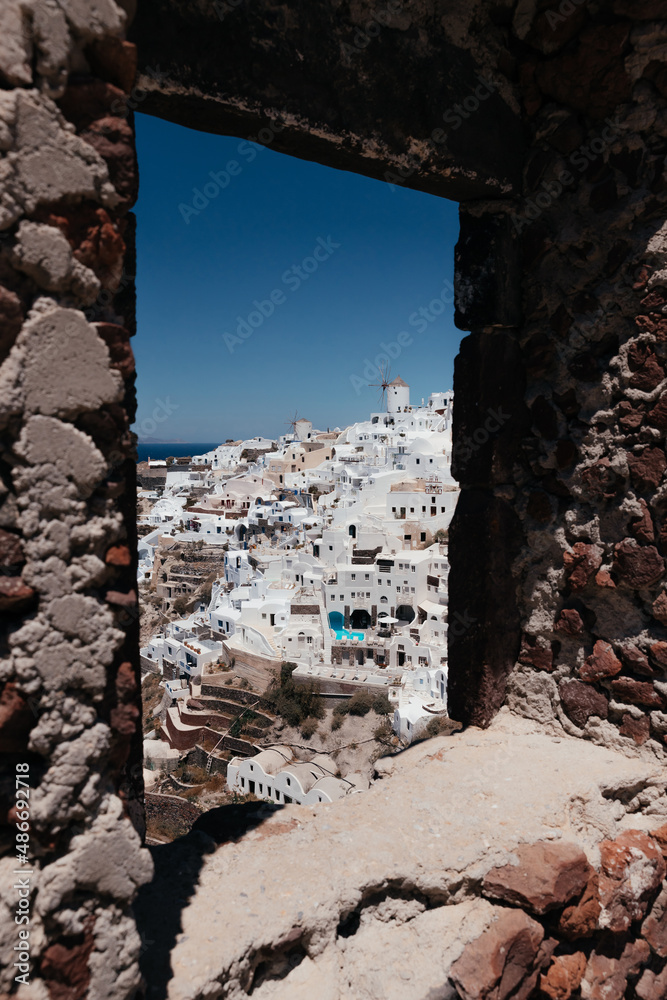 View of Oia town with mills in stone frame in Santorini island in Greece. Summer vacation and holiday concept, luxury travel. Wonderful scenery, cruise ships and white architecture. Amazing landscape