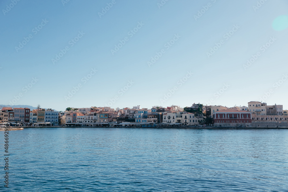 Panorama of colorful buildings and seascape in Chania town on Crete island, Greece. Copy space. Old Venetian harbour of Chania at sunny day with blue sky and water and space for text.