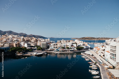 Beautiful view of small town Agios Nikolaos and Voulismeni lake in Crete island  Greece. Place with busy tourist life on the waterfront with cafe and restaurants  boats and mountains on background.