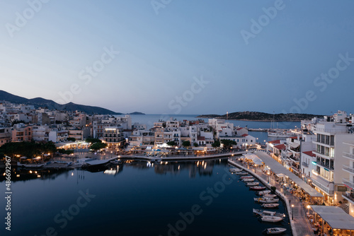Beautiful view of small town Agios Nikolaos and Voulismeni lake in Crete island, Greece. Place with busy tourist life on the waterfront with cafe and restaurants, boats and mountains on background. © Yelyzaveta Kras