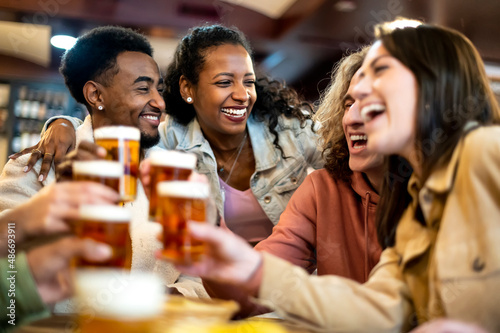 Foto Group of smiling friends drinking and toasting beer at bar restaurant - Friendship concept with young happy people having fun together toasting brew pint on happy hour