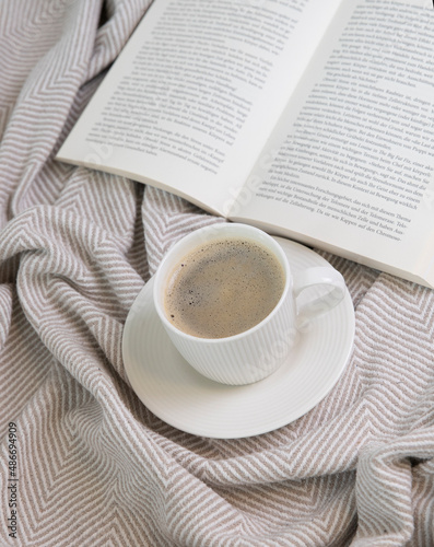 a cup of and a book on a cream blanket 