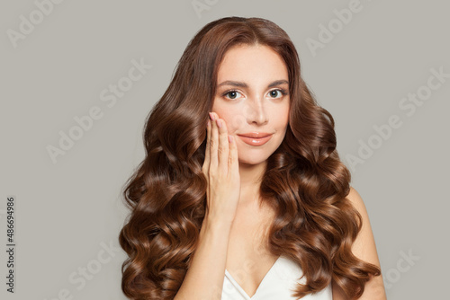 Attractive female model with long shiny brown wavy hair . Beautiful woman with curly hairstyle .
