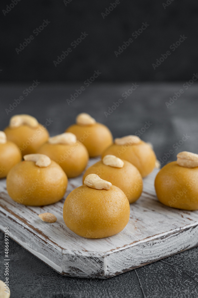 Indian sweets Besan Laddu or Laddoo on a wooden board on a concrete bacground. Roasted chickpea flour with ghee and sugar. Selective focus.