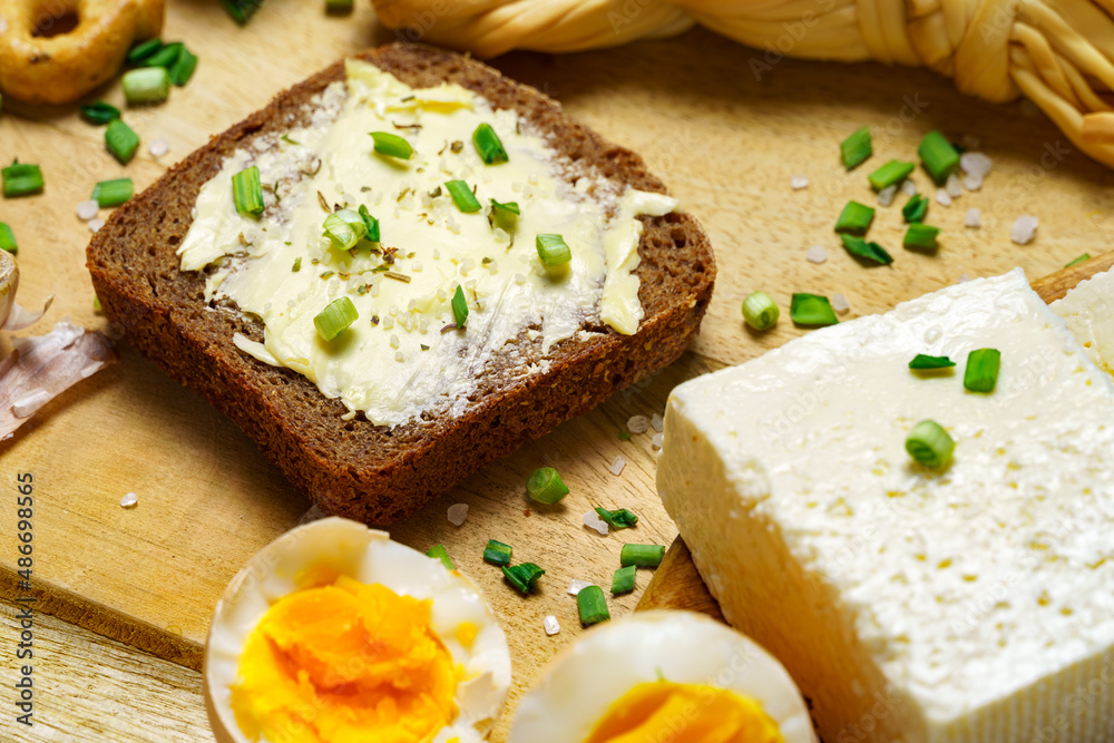 tasty lunch in rural style, healthy food - bread and butter sandwich, feta cheese, eggs, green leek and rye bread, cooked food on a white wooden boards tasty lunch in rural style, healthy food - bread and butter sandwich, feta cheese, eggs, green leek and rye bread, cooked food on a white wooden boards