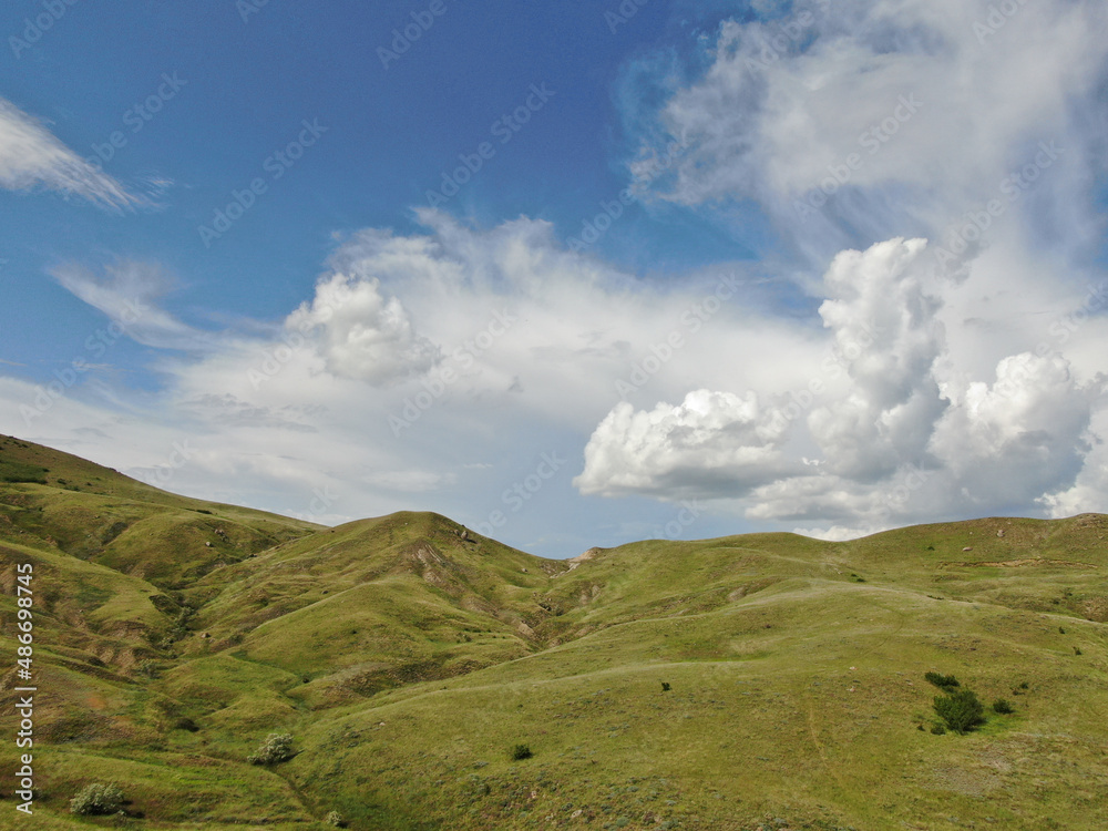 Peaceful landscape green hills under cloudy blue sky