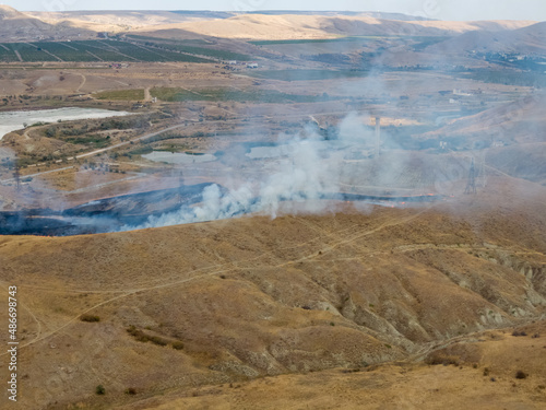 Fire in a hilly autumn valley. A bright sunny day