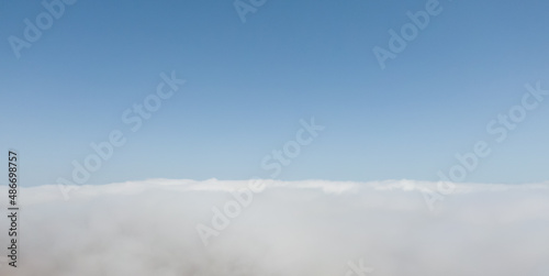 Aerial view of dense fog lying on the ground under a clear blue sky