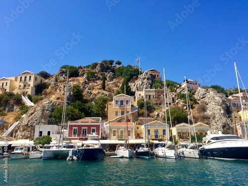 Symi island view from the sea. Aegean Sea. Marina, yachts, colourful houses, mountain. Boats in the harbor. Greece. Dodecanese islands  © Alla