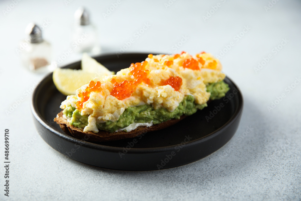 Healthy avocado toast with scrambled eggs and caviar Healthy avocado toast with scrambled eggs and caviar