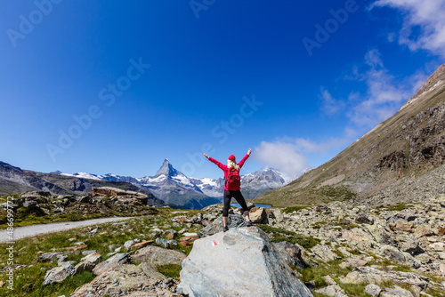 Hiking - hiker woman on trek with backpack living healthy active lifestyle. Hiker girl walking on hike in mountain nature landscape in Swiss alps, Switzerland.