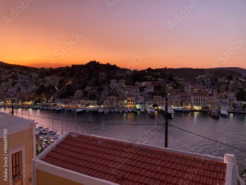 Sunset above Symi island, Greece. Dodecanese islands. Sunset above Symi island,Greece. Vanilla sky. Town lights, yacht moored in marina. Dream destination. Vanilla sky. Mountains