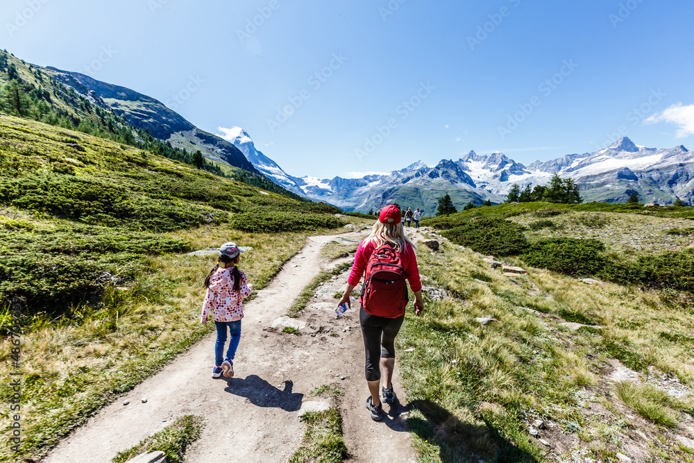 Hiking - hiker woman on trek with backpack living healthy active lifestyle. Hiker girl walking on hike in mountain nature landscape in Swiss alps, Switzerland.