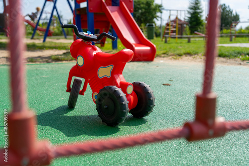 Red children's tricycle on a colorful modern playground.
