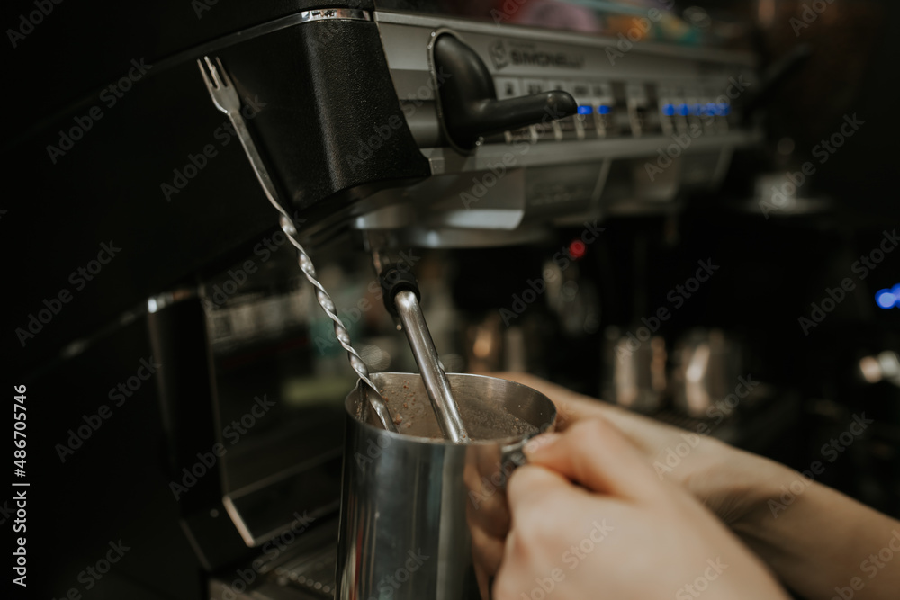 A young girl makes coffee on a coffee machine.