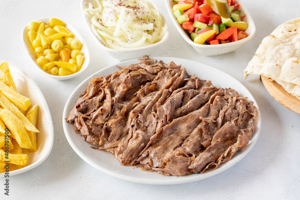 Doner kebab on a white background. Traditional Turkish cuisine flavor meat doner. With lavash bread, french fries, salad and onions on the side Doner kebab on a white background. Traditional Turkish cuisine flavor meat doner. With lavash bread, french fries, salad and onions on the side
