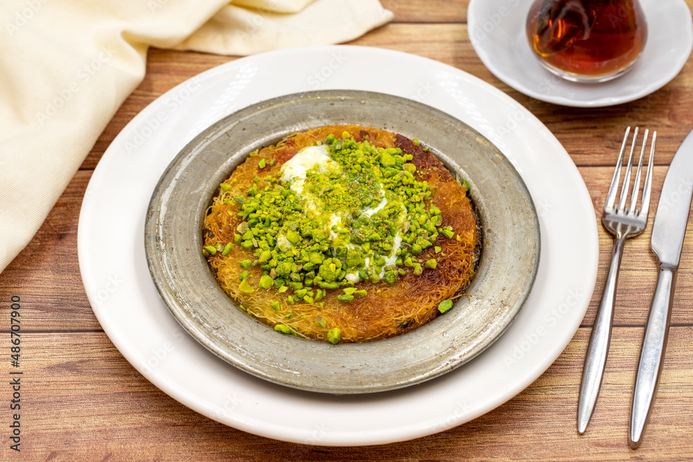 Pistachio kunefe on wooden table. Traditional Turkish cuisine flavor Pistachio kunefe on wooden table. Traditional Turkish cuisine flavor