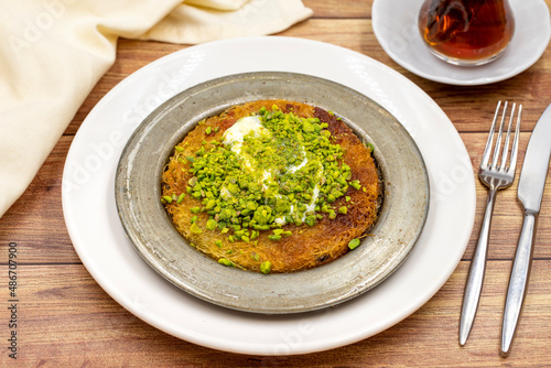 Pistachio kunefe on wooden table. Traditional Turkish cuisine flavor photo