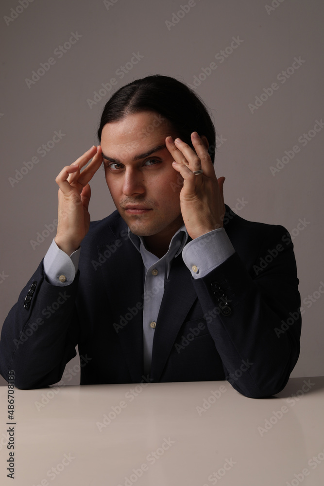 Handsome bearded man in trendy suit with hands touches his head. Vertical. Handsome bearded man in trendy suit with hands touches his head. Vertical.