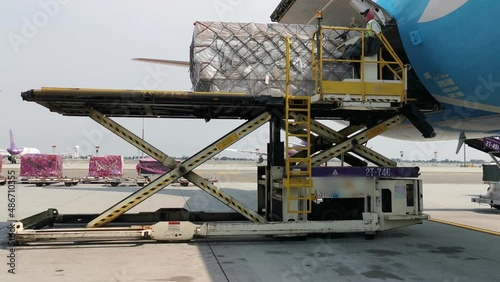 A worker is loading a cargo containers from the freighter airplane at the airport. In the logistic industry the air transport is very popular.