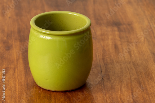 Clay small green pot. Clay pot on a wooden background. 