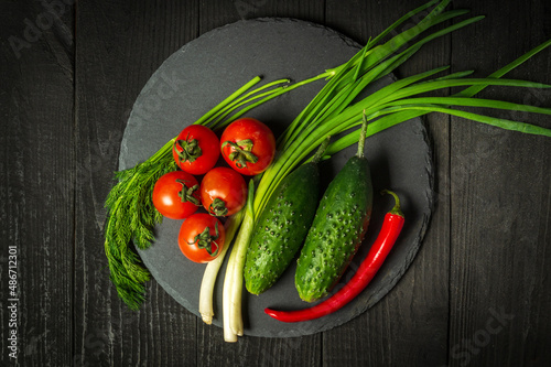 Big set for fresh vegetable salad. Red tomatoes and green young onions with cucumber on a vintage brown plate