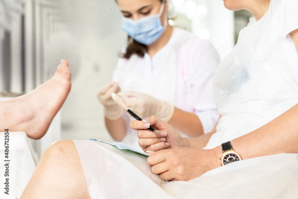 Beauty course training - leaning pedicure step by step. Training for pro nail technician, beauty expert. Practitioner training in pedicure, beauty salon. Nail Technician Instructor with her student Beauty course training - leaning pedicure step by step. Training for pro nail technician, beauty expert. Practitioner training in pedicure, beauty salon. Nail Technician Instructor with her student