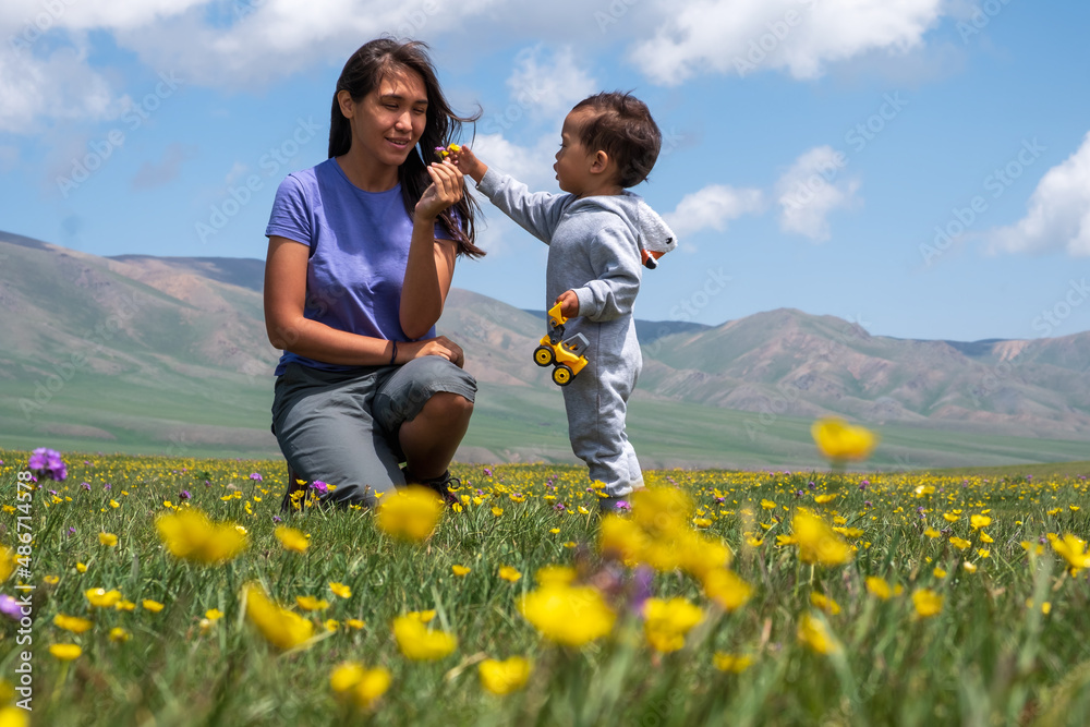 Mother and son laying on blooming mountain valley. Happy family leisure. Outdoor family recreation concept. Mother and son laying on blooming mountain valley. Happy family leisure. Outdoor family recreation concept.