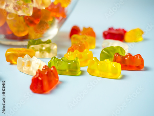 Bowl with tasty bright gummy bears on blue table