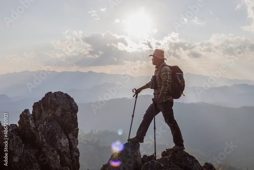 Male Hiker standing on top mountain sunset background. Hiker men's hiking living healthy active lifestyle.