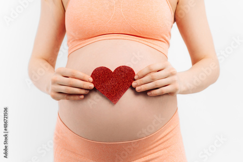 Wallpaper Mural Young pregnant woman holding and touching her belly, holding a red heart sign, belly close-up Torontodigital.ca