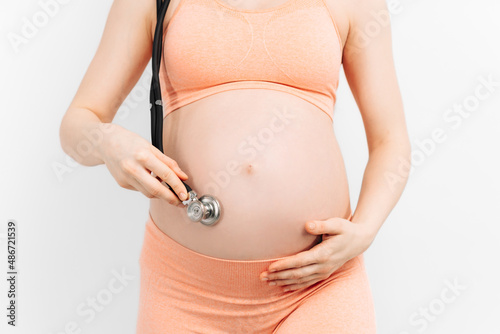 Belly of a pregnant woman and a stethoscope. Checking and listening to the sound of the fetus with a stethoscope photo