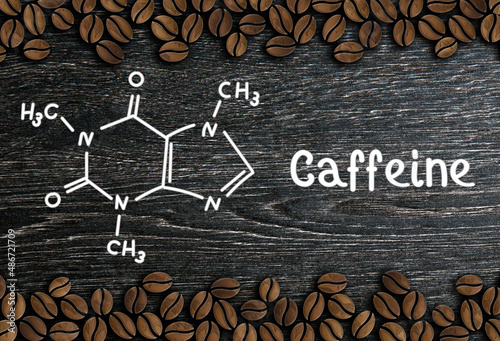 coffee beans with inscription and chemical structure of caffeine on a wooden background